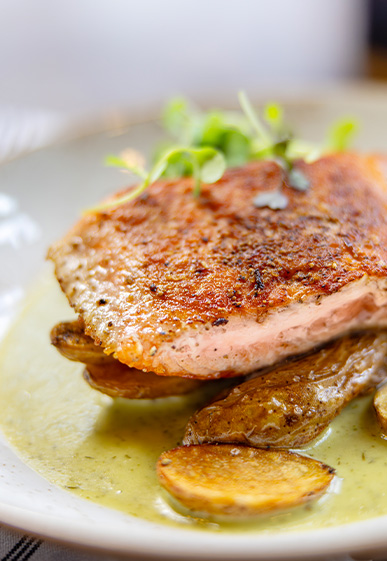 Salmon on top of small potatoes in a sauce. 