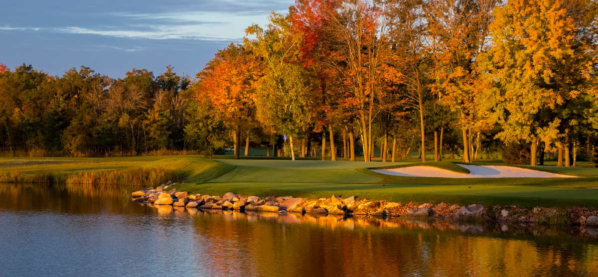 Water hazard next to a fairway with trees changing colors in the fall