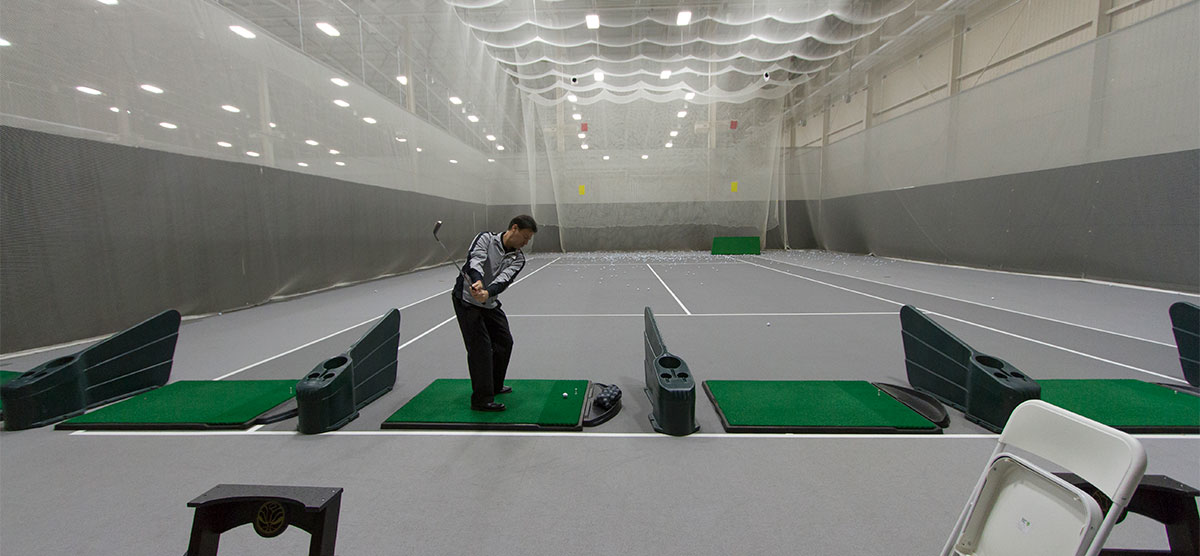 Golfer hitting off a practice mat at the indoor driving range at SentryWorld