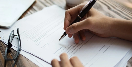 hand with pen signing a document