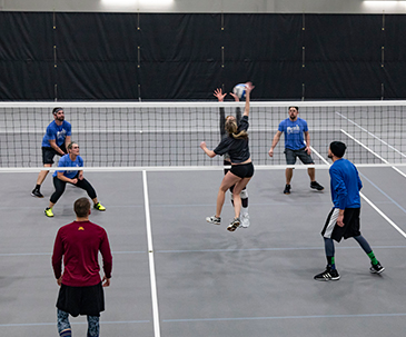 People playing indoor volleyball on the courts in the fieldhouse