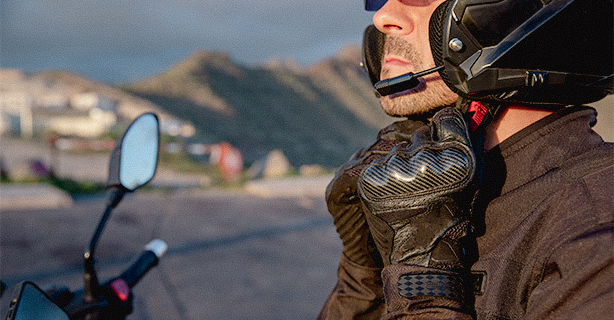 A motorcyclist puts on his helmet while sitting on his motorcycle