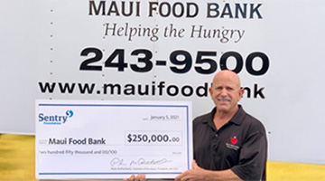 Maui Food Bank representative holding donation check