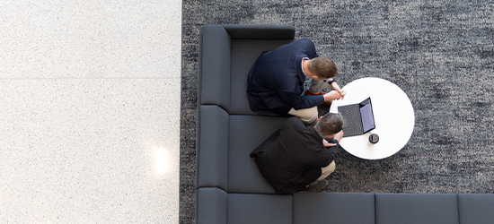 two men sitting on couch working in an office setting