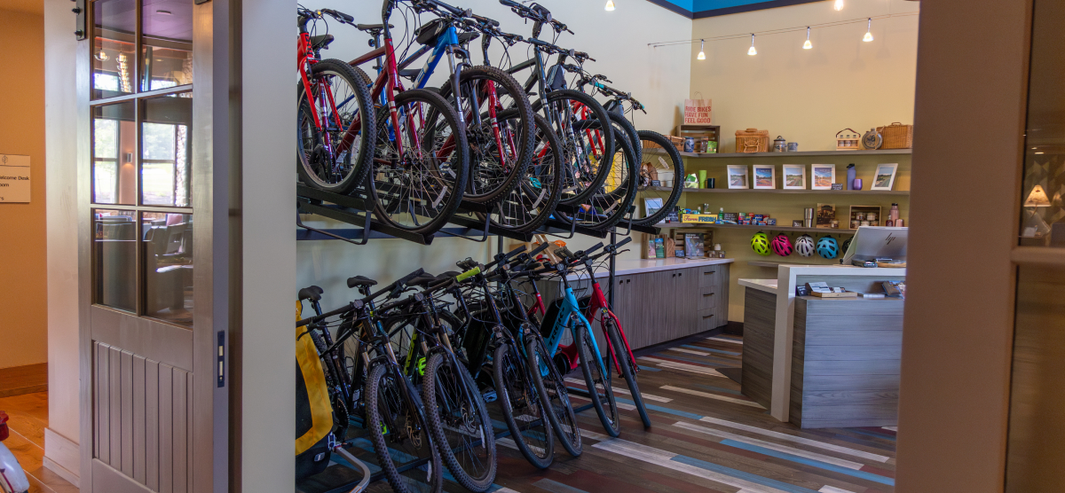 Indoor bike rental shop with many bicycles on display and a counter with merchandise.