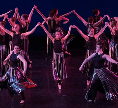 Dancers on a stage dressed in black. 