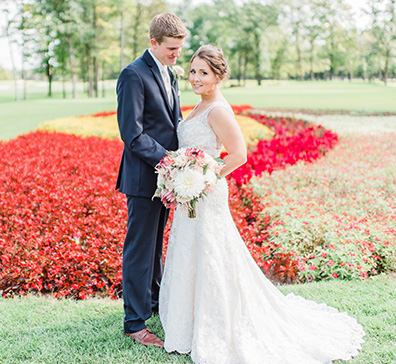 Bride and groom posing in front of the flower hole on the SentryWorld golf course