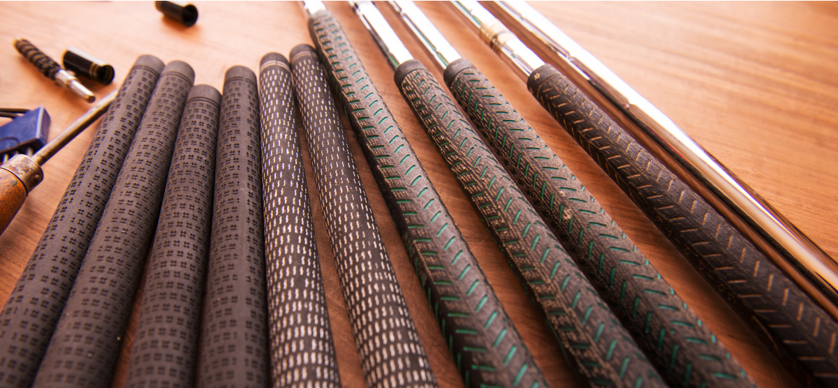Golf club grips being changed on a wood table. 