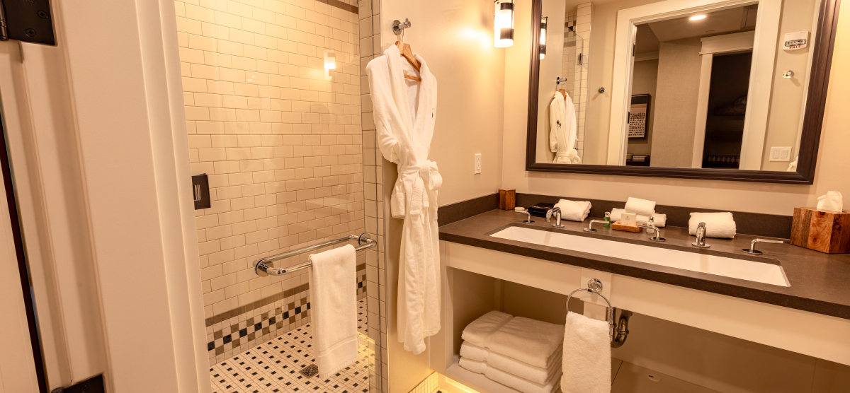 Executive level bathroom with white robe and walk in shower. 