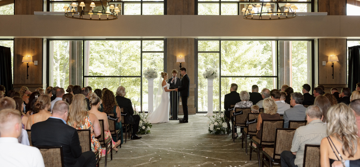 Guests watch the bride and groom at the altar during an indoor wedding ceremony.
