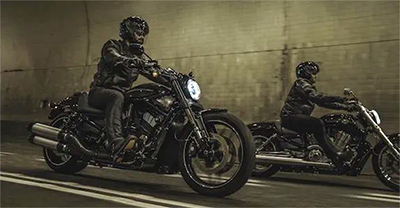 Two people riding motorcycles at night