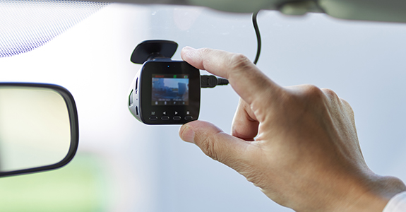 person adjusting dash camera on vehicle