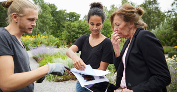 Three people reviewing a report while standing outside