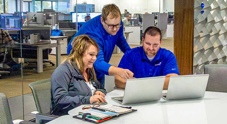 Three people working together in a conference room at Sentry Home Office.