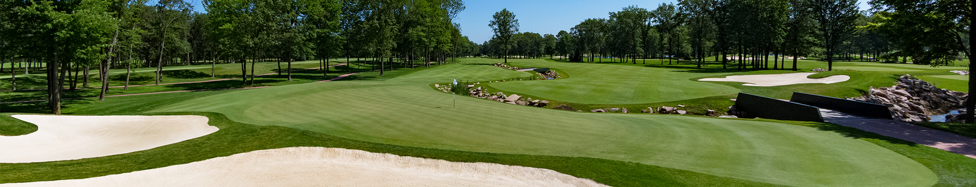 Sand traps and a small bridge next to a putting green on the SentryWorld golf course