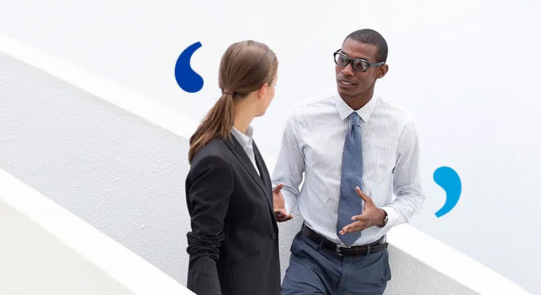 A man and a woman having a conversation in an office building.