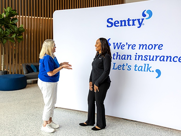 teams-human-resources-696x522 Two people talking in front of a Sentry sign.
