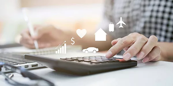 hand typing into a calculator and financial icons hovering above it