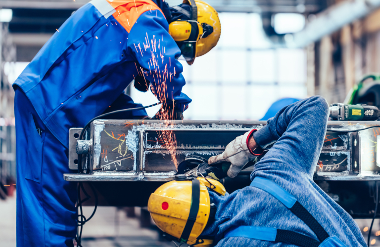 Two welders working on a metal piece.