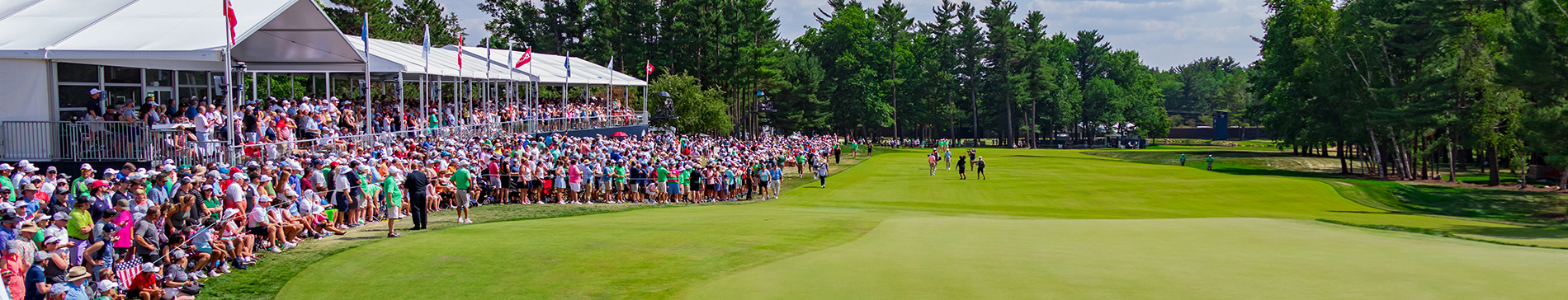 Fans standing along the 18th hole watching the 2023 U.S. Senior Open players golf