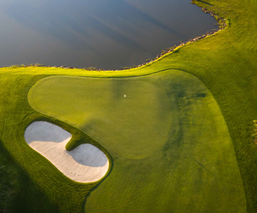 Aerial view of a putting green next to a water hazard and a sand trap