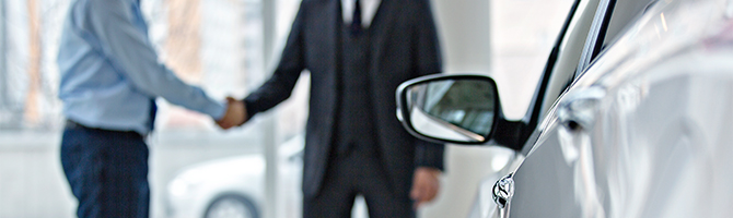 Two people shaking hands at dealership