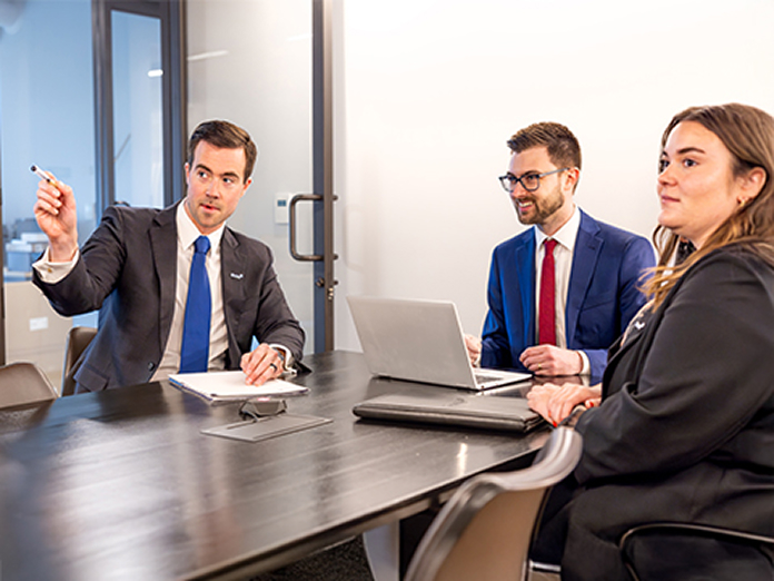 Three people in a meeting discussing something on a screen
