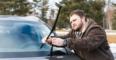 Inspecting windshield wipers on car