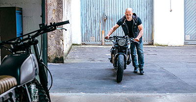 Man pushing a motorcycle into a storage garage