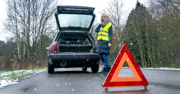Woman wearing safety vest standing outside of car while on phone