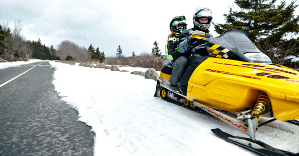 Two snowmobile riders on a snowy road