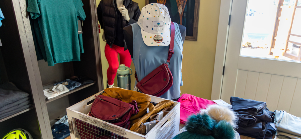 Retail display with a mannequin, hat, bags, and clothing items in a store.