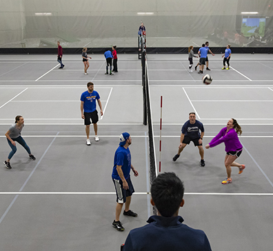 People playing volleyball on a court in the fieldhouse