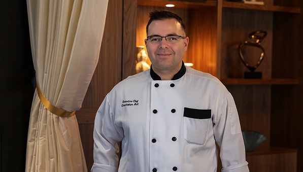 50-50-chef-chris-dinner-597x339 Executive Chef Chris Ault in a white chef’s coat smiling.