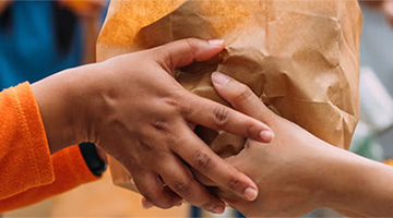 Volunteer worker handing off packaged goods for donation