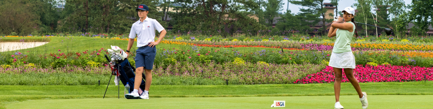 Golfer with a caddie at a tee box on the golf course.