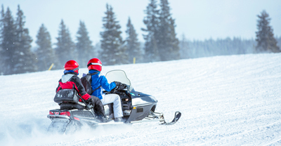 Couple snowmobiling on snowy hill