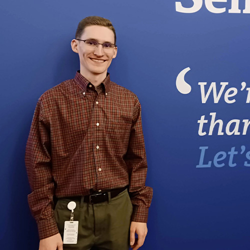 Scholarship recipient standing in front of banner