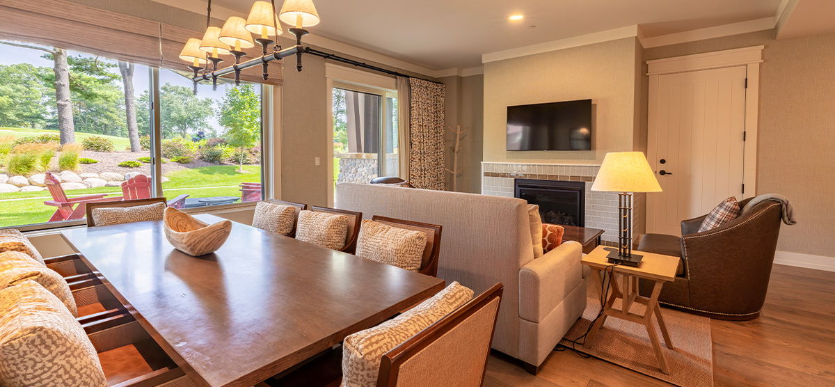 carousel-suite-golf-view-queen-5-1200x556 Suite parlor room with dining room table and sitting area.