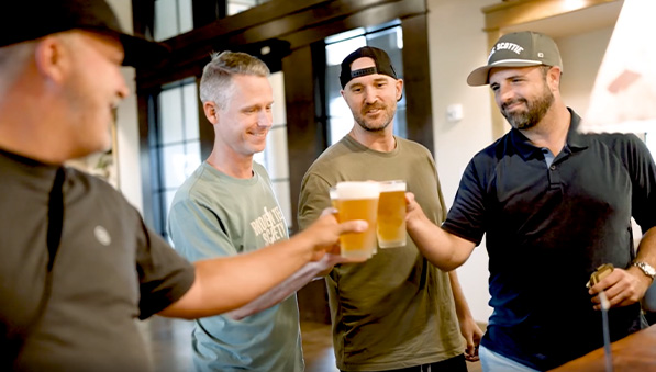 Group of men holding glasses of beer as they check into the Inn at SentryWorld.