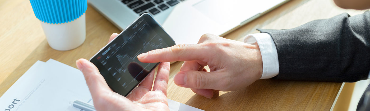 Business man at desk checking graph on phone