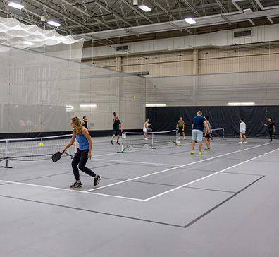 image-card-contact-fieldhouse-396x364 People playing pickleball on an indoor court.