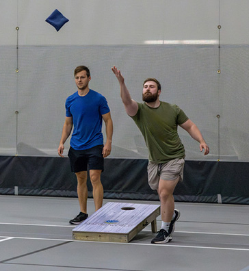 Man throwing a bean bag in the SentryWorld fieldhouse