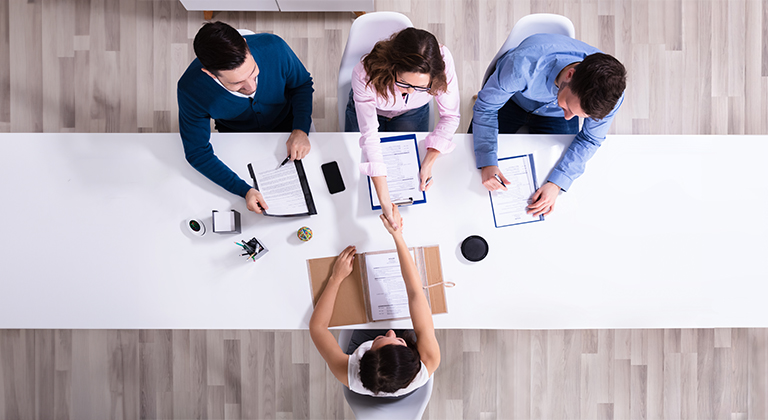 Aerial view of three people interviewing a candidate.