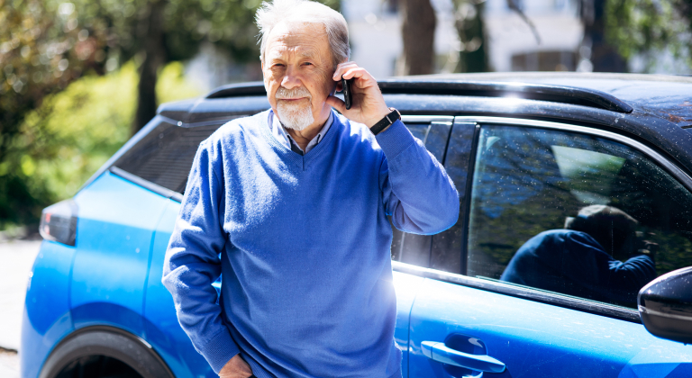 Man stands next to vehicle while on phone.