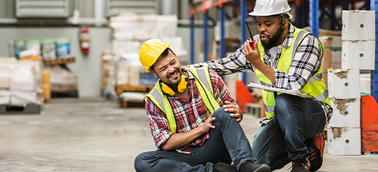 Injured warehouse worker attended to by coworker