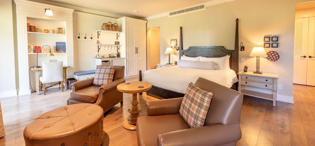 King size bed with two chairs and ottoman in front. 
