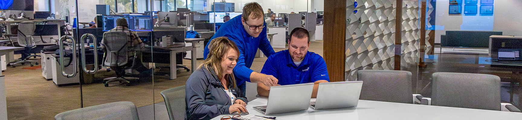 Three people working together in a conference room at Sentry Home Office.