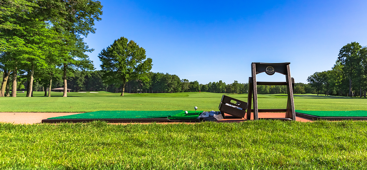 Golf balls teed up on a practice mat at the outdoor SentryWorld driving range