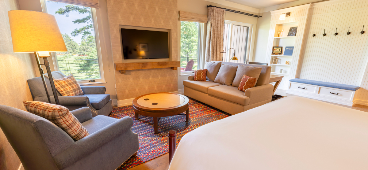 King size bed with two chairs and a loveseat in front of a fireplace. 